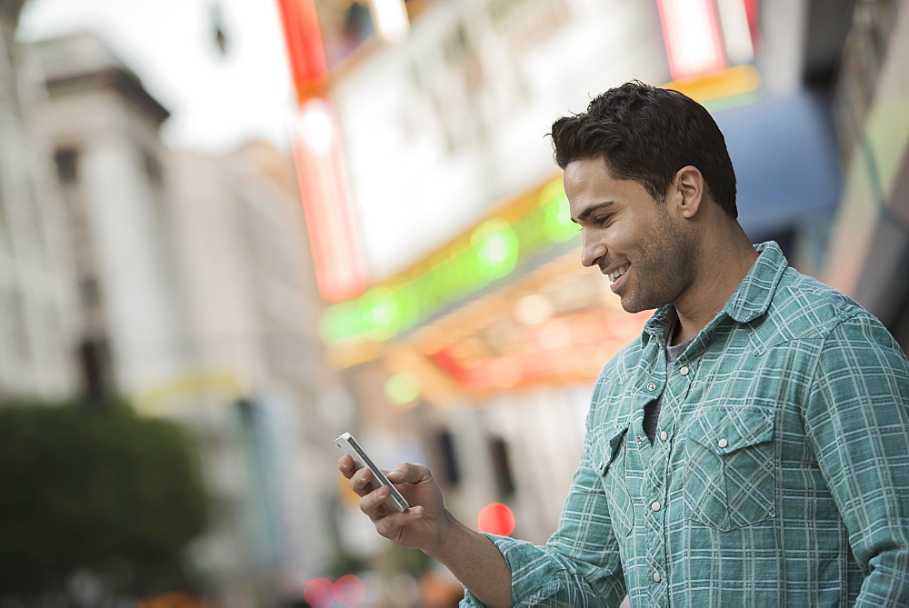 A man checking his phone on a city street, United States of America