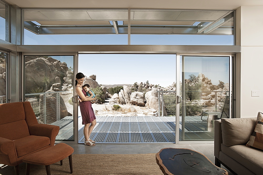 A woman and a young child in the living space of an eco house in the desert, United States of America