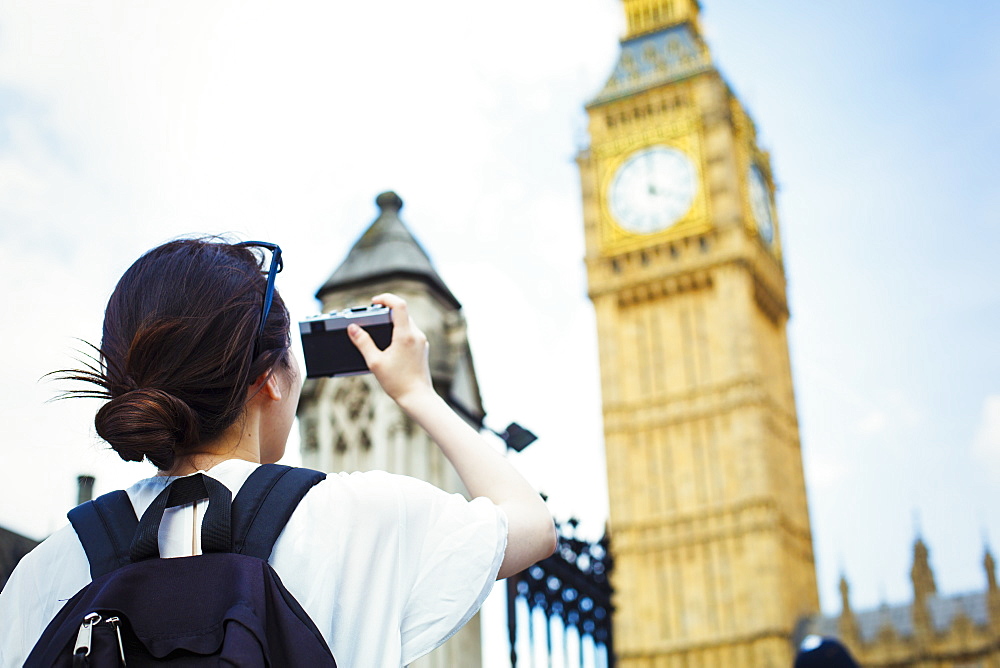 Young Japanese woman enjoying a day out in London, taking a picture of Big Ben, United Kingdom