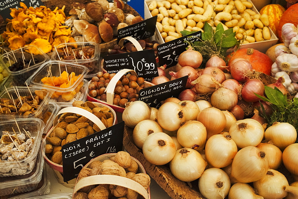 A market stall with display of fresh vegetables, onions, potatoes, walnuts and mushrooms, France