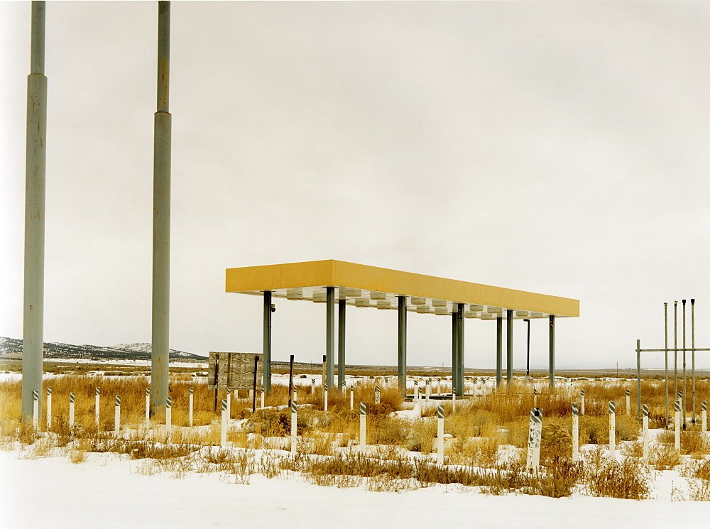 An abandoned gas station, petrol station in the middle of nowhere, plants growing over the forecourt, USA