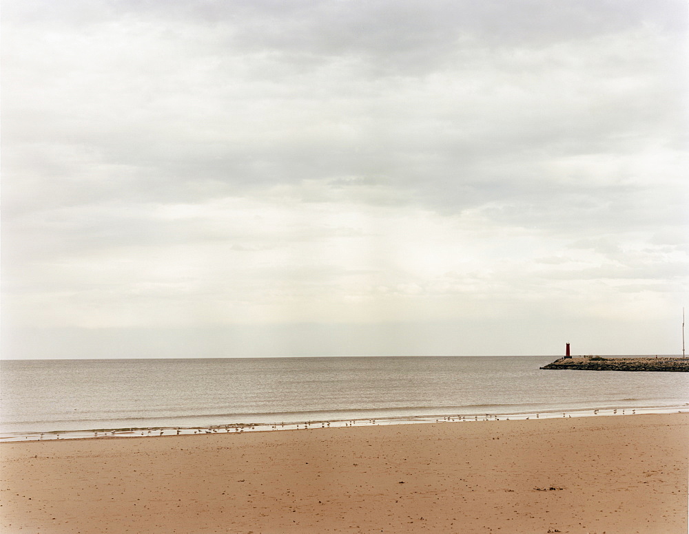 A beach and view to the end of a pier jutting out into the sea, USA