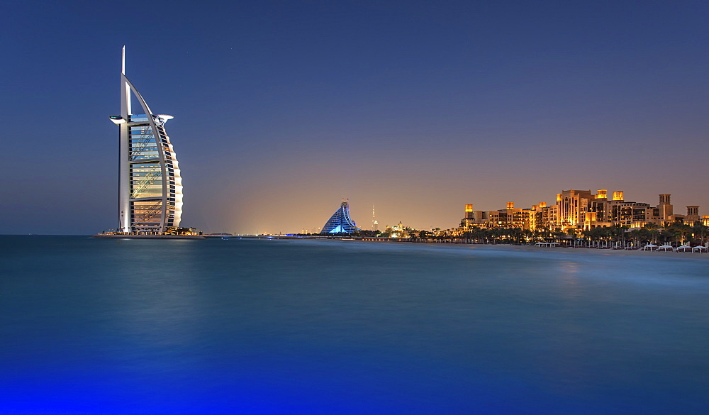 Cityscape of Dubai, United Arab Emirates at dusk, coastline of Persian Gulf with illuminated Burj Al Arab skyscraper in the distance, Dubai, United Arab Emirates