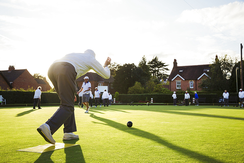 A lawn bowls player standing on a small yellow mat preparing to deliver a bowl down the green, the smooth grass playing surface, England, United Kingdom