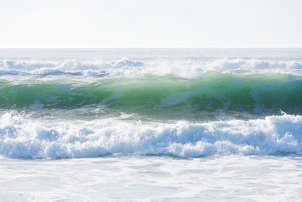 Seascape with breaking waves on sandy beach.