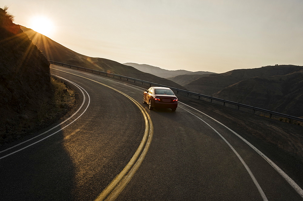 A view from behind of an automobile going around a curve at sunset in eastern Washington State, United States of America