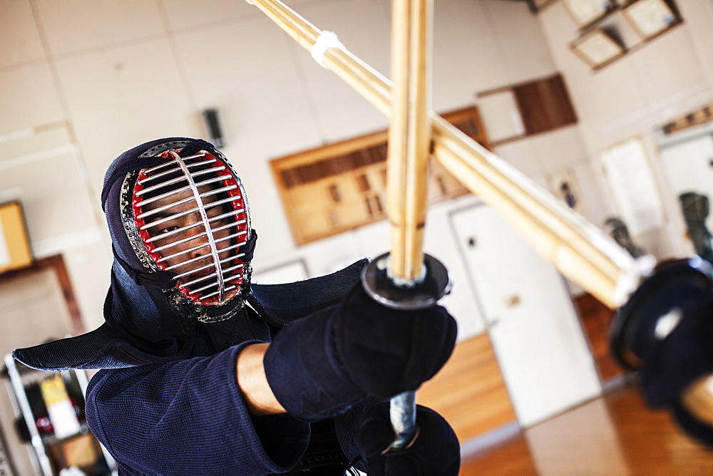 Two Japanese Kendo fighters wearing Kendo masks practicing with wood sword in gym, Kyushu, Japan