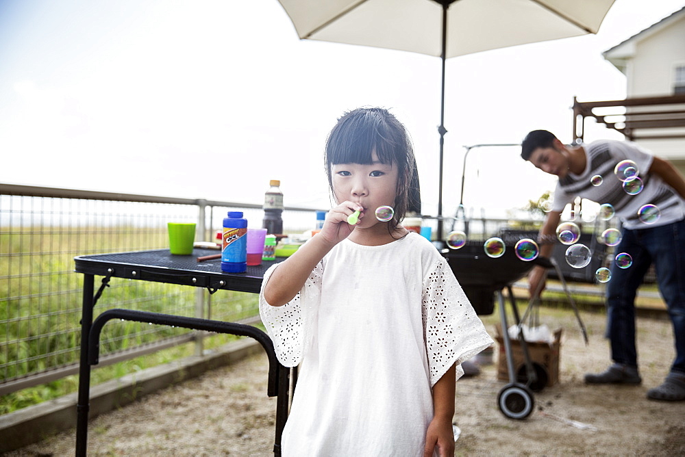 Portrait of Japanese girl wearing white shirt blowing soap bubbles, Kyushu, Japan