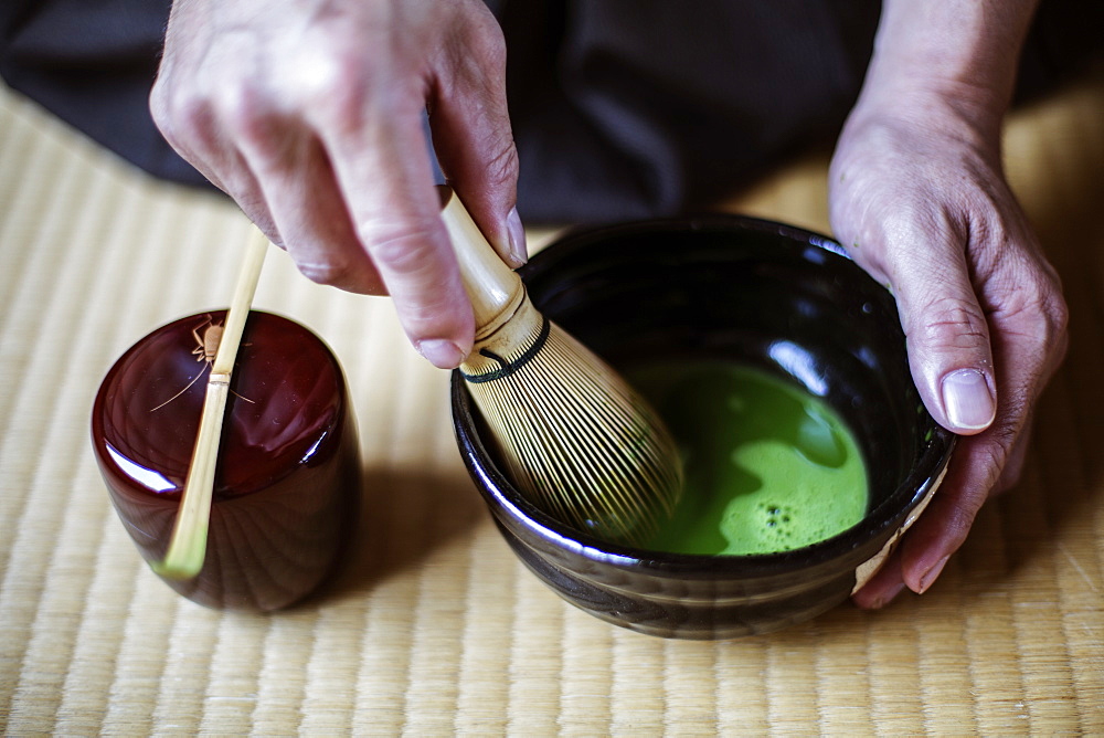 High angle close up of traditional Japanese Tea Ceremony, man using bamboo whisk to prepare Matcha tea, Kyushu, Japan