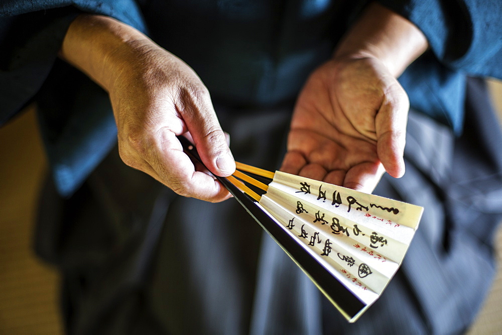 High angle close up of Japanese man wearing kimono holding Sensu fan, Kyushu, Japan