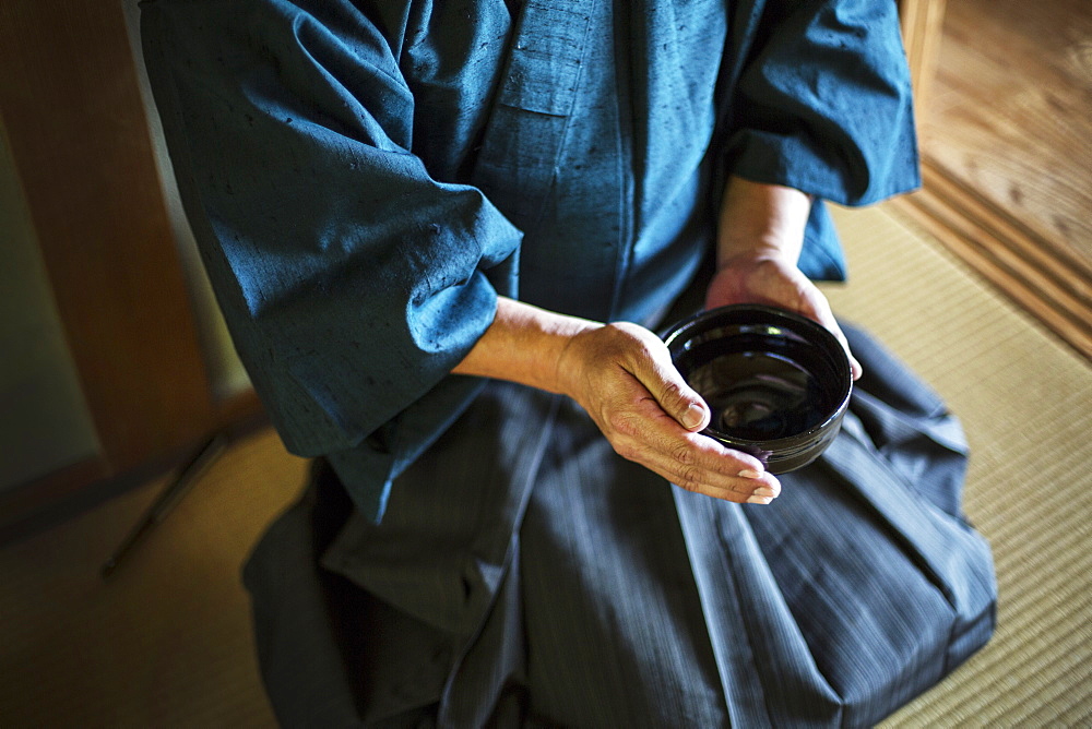 High angle close up of Japanese man wearing kimono holding tea bowl during tea ceremony, Kyushu, Japan