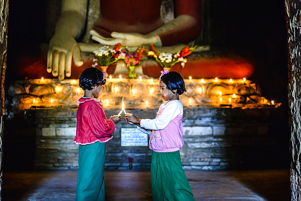 Asian girls lighting candles in Buddhist temple