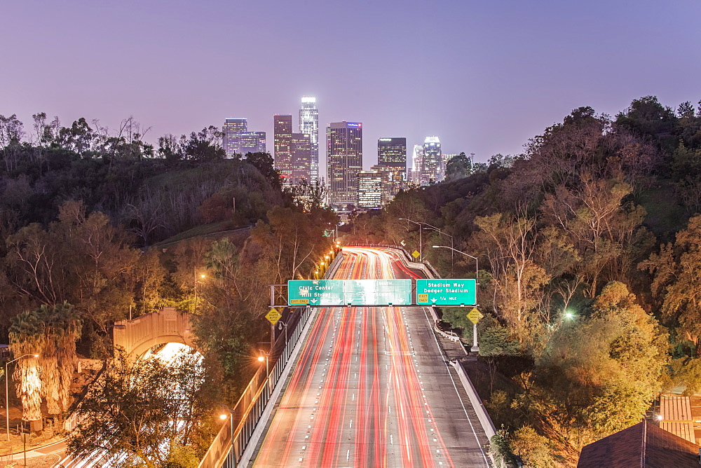 Los Angeles city skyline over busy highway illuminated at night, California, United States