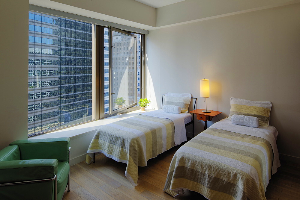 Twin beds in bedroom overlooking city skyscraper