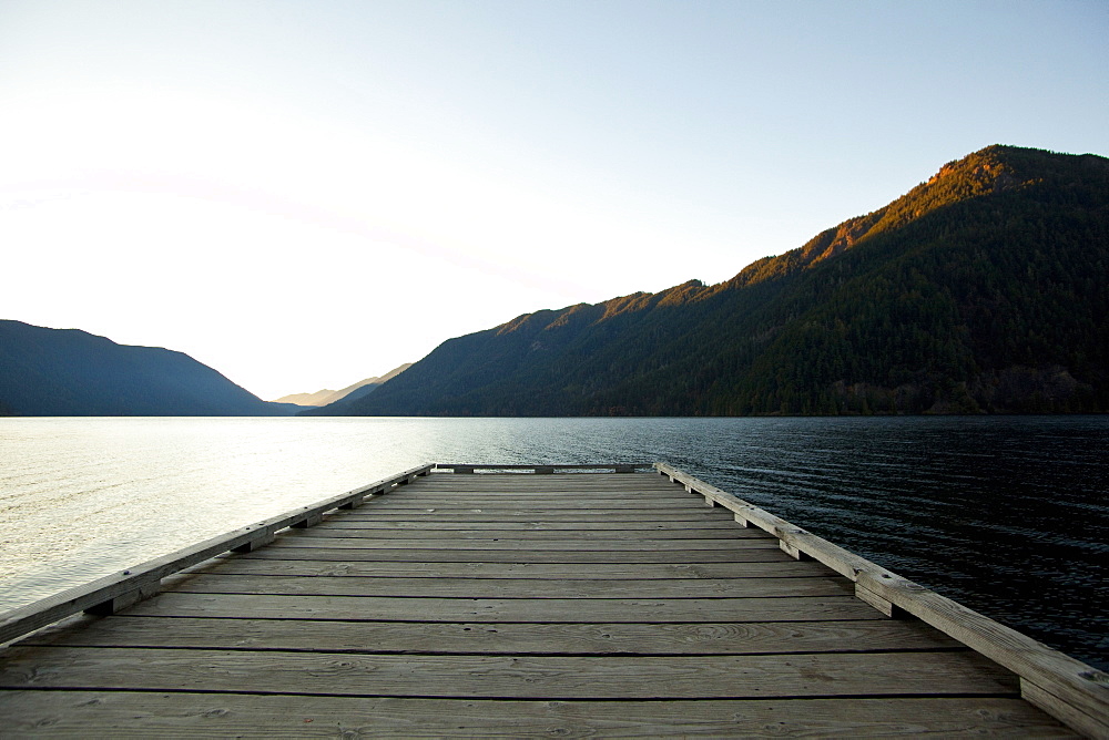 Wooden deck at lake under blue sky