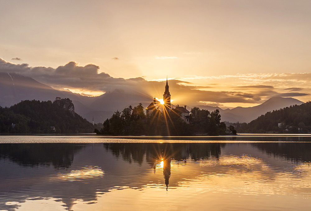 Sunrise over church tower reflected in still lake, Bled, Upper Carniola, Slovenia