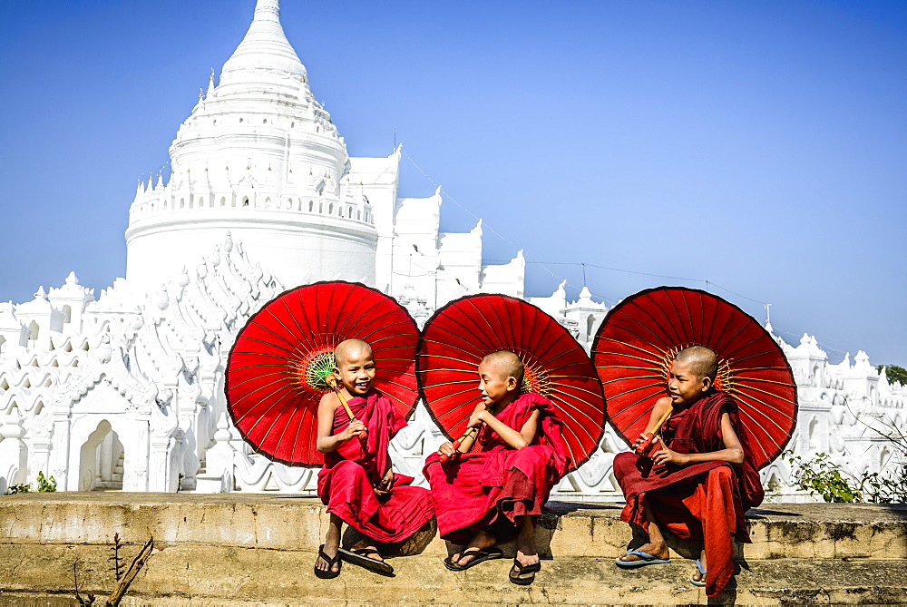 Asian monks sitting under umbrellas near historic temple, Mingun, Mandala, Myanmar