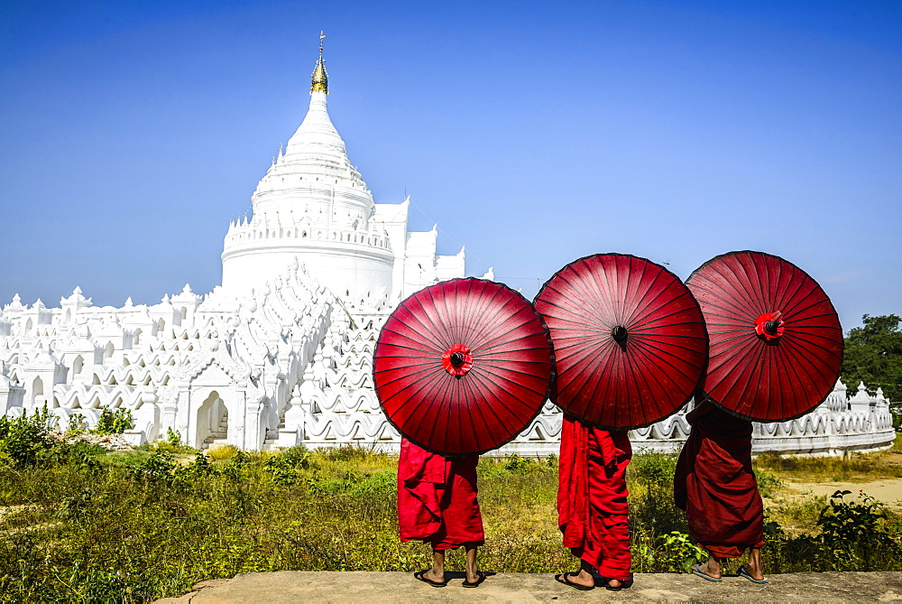 Asian monks under umbrellas viewing historic temple, Mingun, Mandala, Myanmar