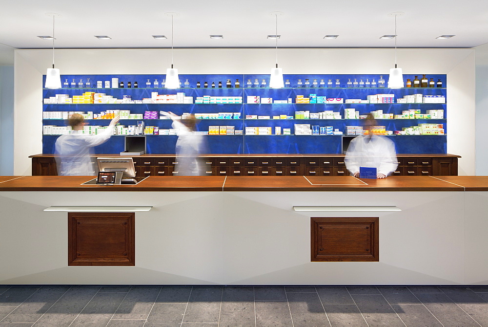 Blurred view of pharmacists behind counter in modern pharmacy