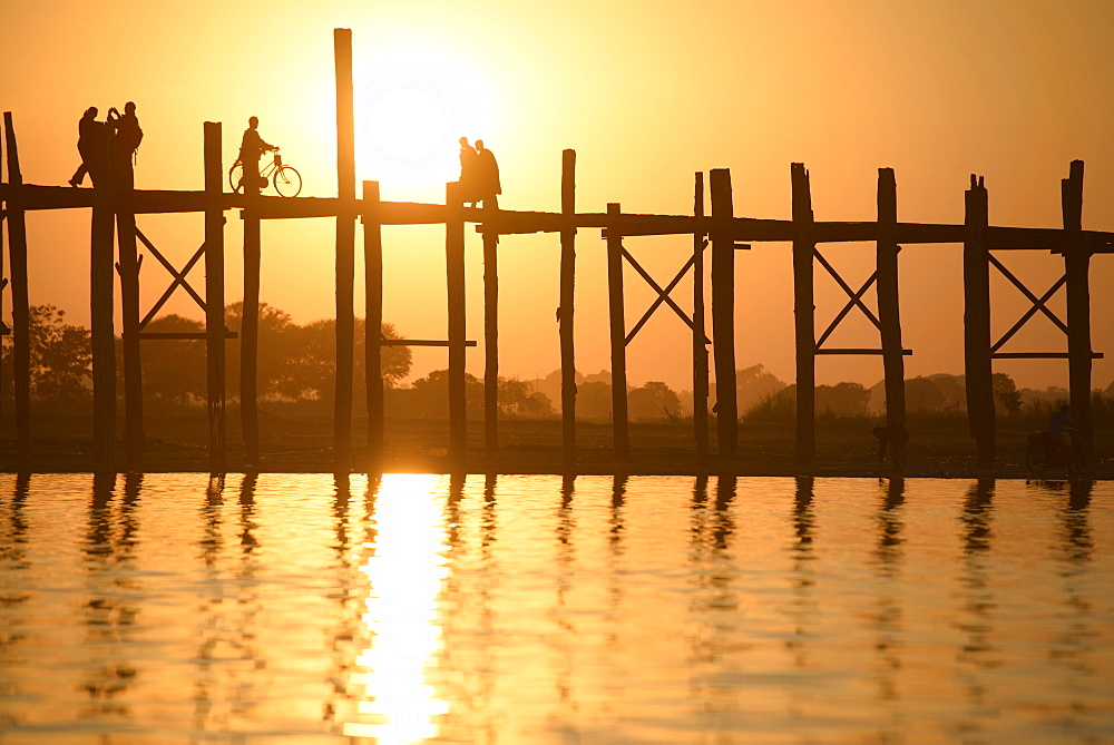 People walking on elevated wooden walkway at sunset, Myanmar, Burma