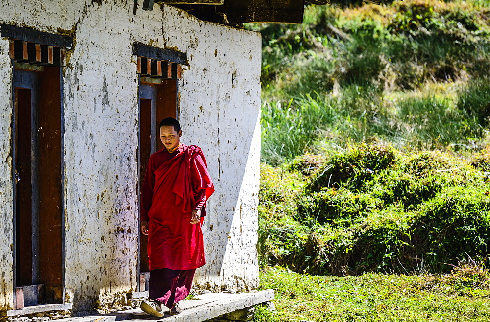 Asian monk walking by monastery doors, Bhutan, Kingdom of Bhutan