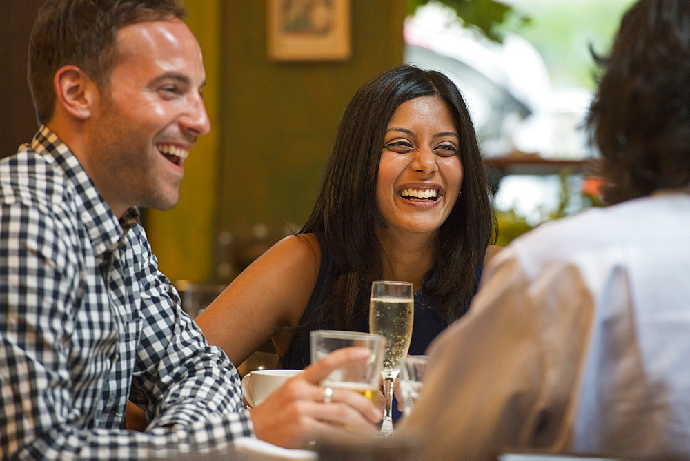 Business people out and about in the city. Three people seated around a table in a bar or cafe, having drinks.