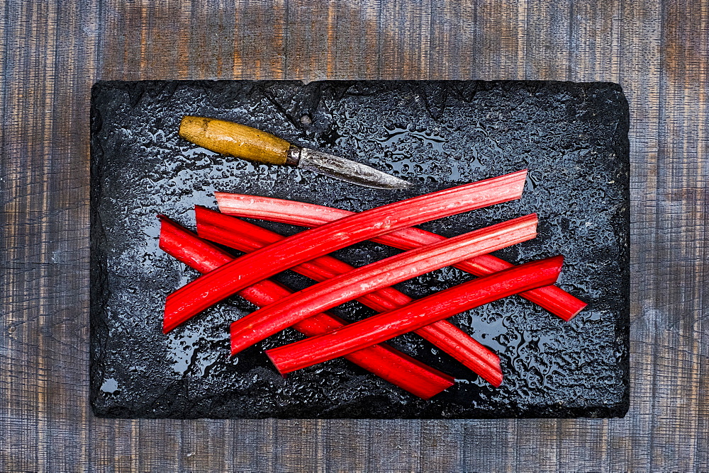 High angle close up of rhubarb stalks and knife on black slate, Oxfordshire, England