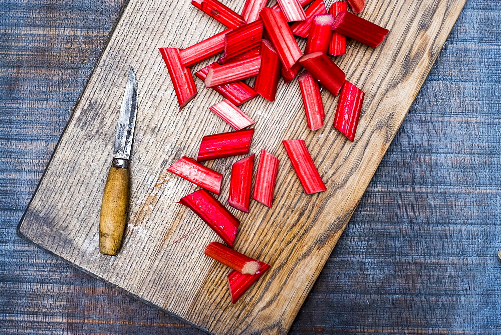 High angle close up of slices of rhubarb and knife on wooden cutting board, Oxfordshire, England