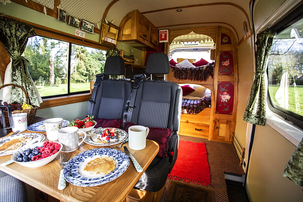 Interior view of camper van with breakfast on table, Oxfordshire, England