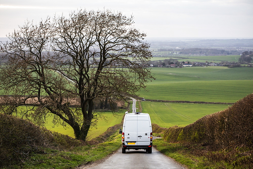 Rear view of camper van driving down a country lane, Oxfordshire, England