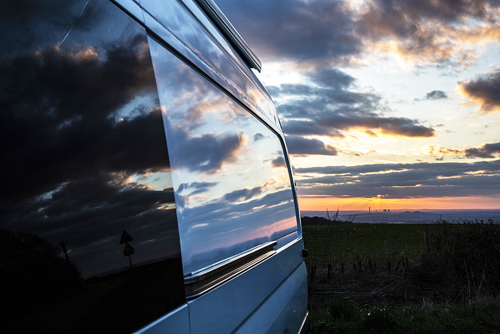 Reflections of clouds on camper van window at sunset, Oxfordshire, England