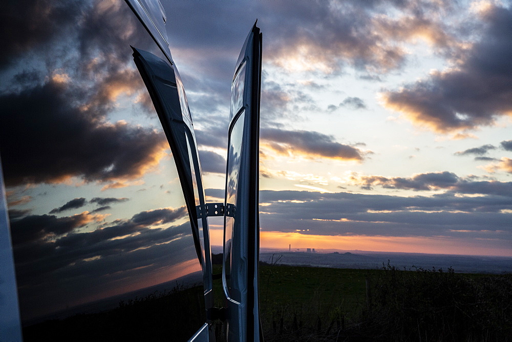 Reflections of clouds on camper van window at sunset, Oxfordshire, England