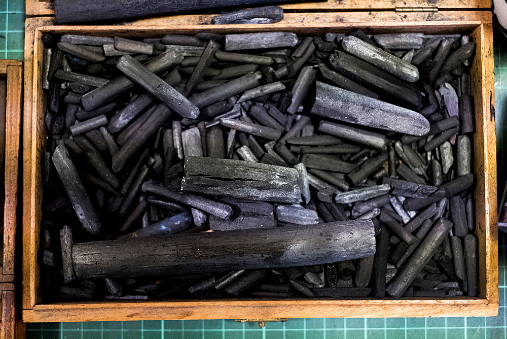 High angle close up of wooden box with a selection of artist's charcoal sticks in different sizes, Oxfordshire, England