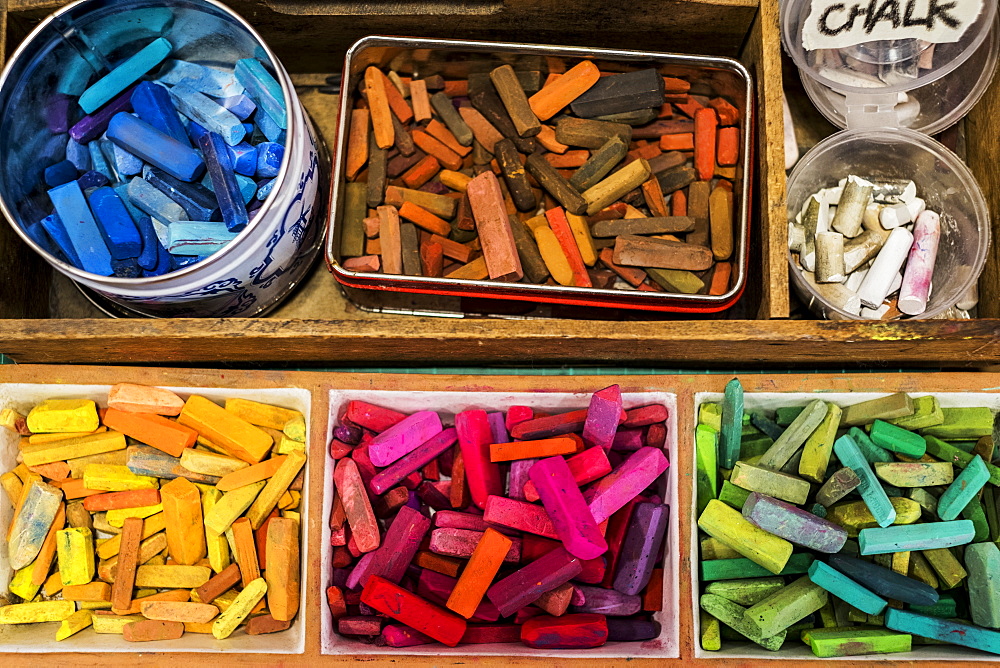 High angle close up of a wooden box with artist's crayons in a variety of vibrant colours, Oxfordshire, England