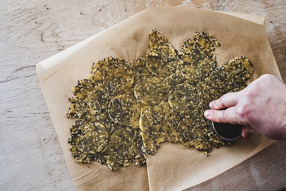 High angle close up of person cutting discs of seeded cracker dough, England