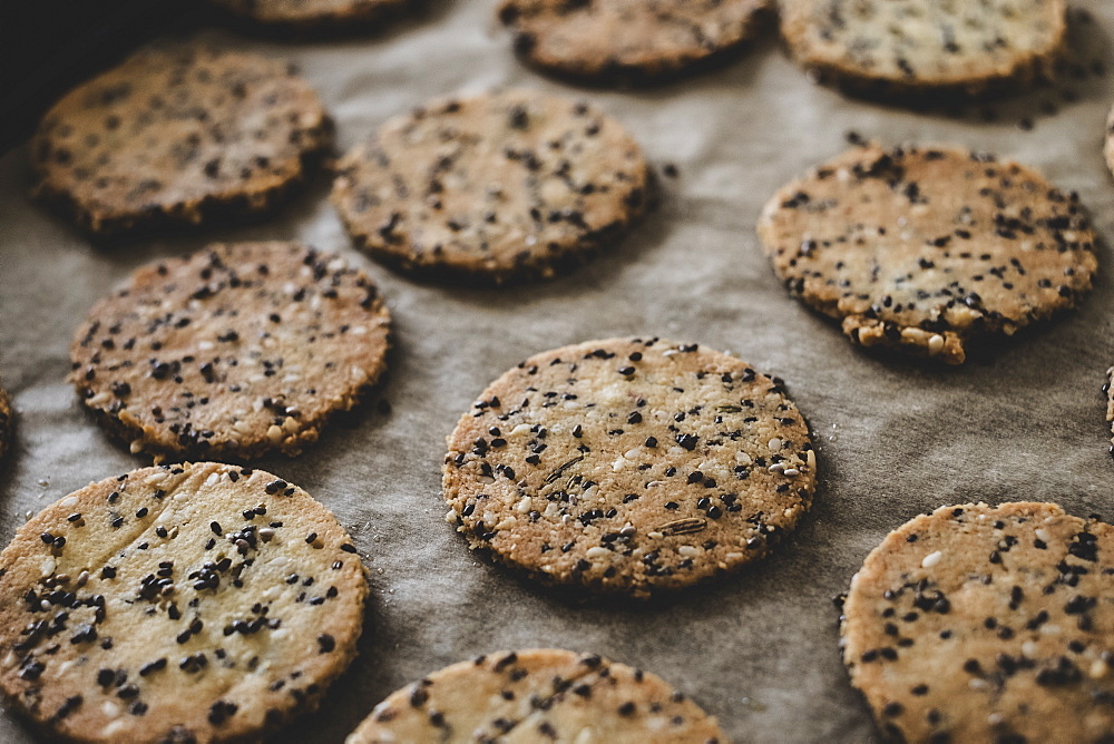 High angle close up of freshly baked seeded crackers on a baking tray, England