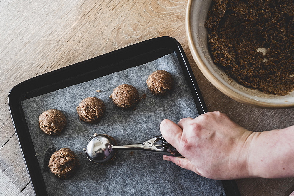 High angle close up of person putting chocolate cookie dough on a baking tray, England