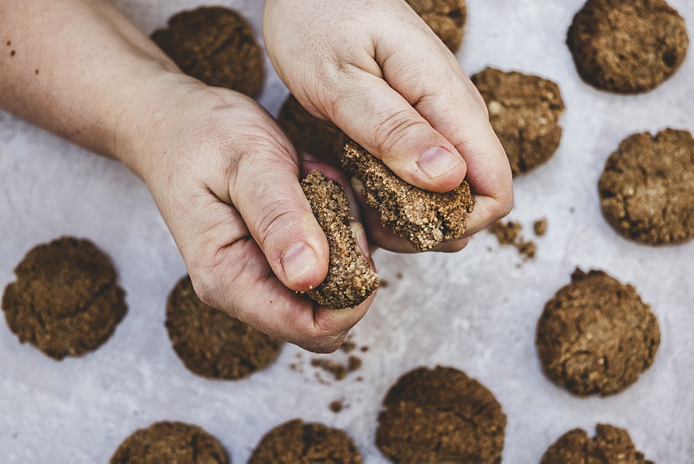 High angle close up of person breaking freshly baked chocolate cookie in half, England