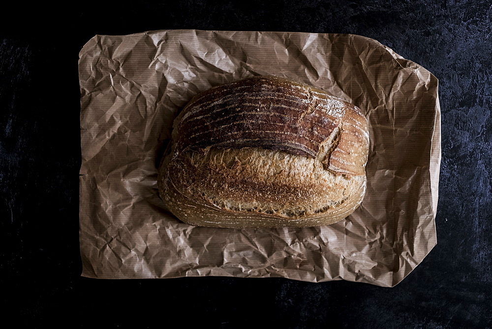 A fresh loaf of baked bread on a brown paper bag, England