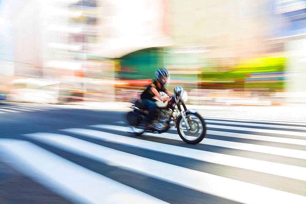 Motion blurred shot of a motorbike at speed on a pedestrian crossing in Tokyo, Japan