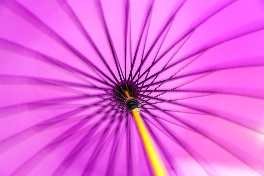 Motion blurred spinning close up of a traditional purple Japanese parasol or umbrella with a bamboo handle