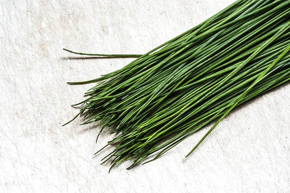 High angle close up of a bunch of fresh chives on white background