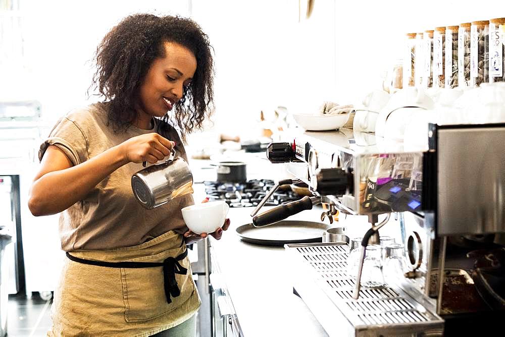 Woman barista preparing a cup of coffee in a coffee shop