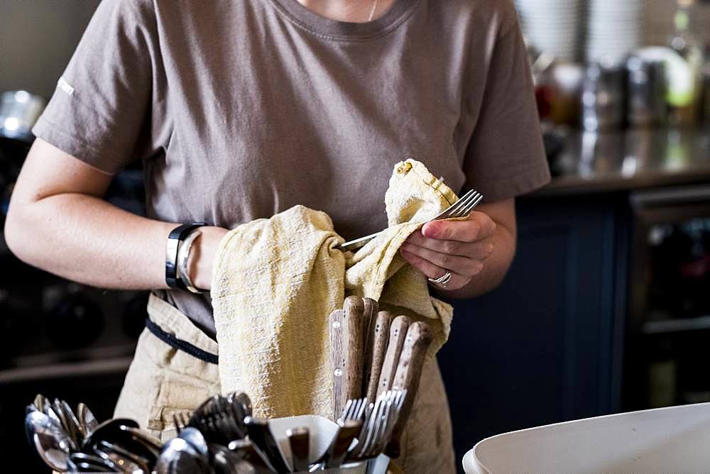 A staff member drying cutlery in a cafe