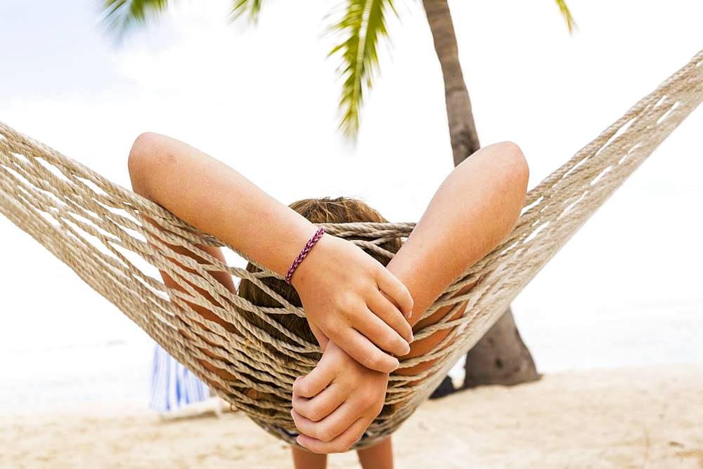 A teenage girl relaxing in a hammock, Grand Cayman, Cayman Islands