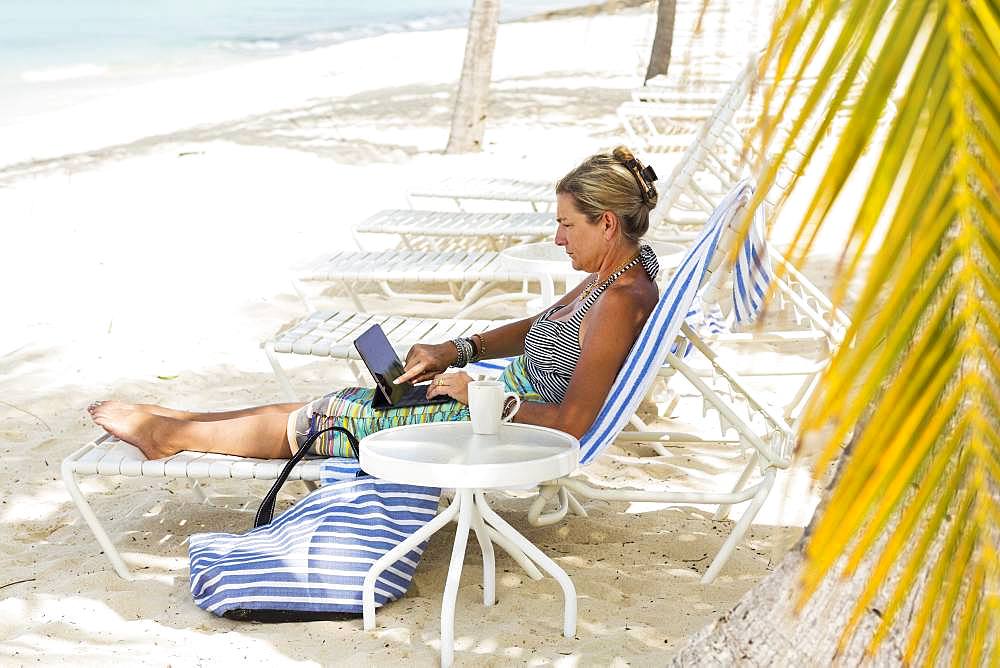 adult woman executive using laptop on the beach , Grand Cayman, Cayman Islands