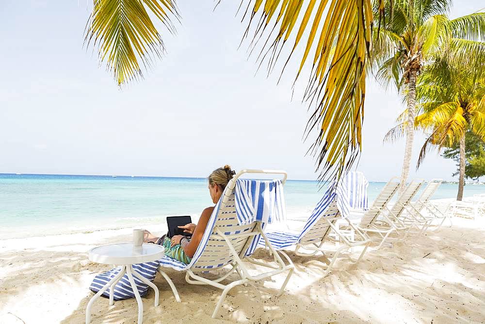 adult woman executive using laptop on the beach , Grand Cayman, Cayman Islands