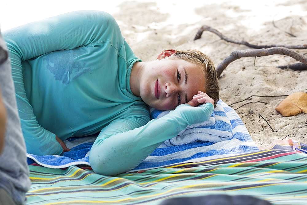 A teenage girl resting on a beach towel, Grand Cayman, Cayman Islands