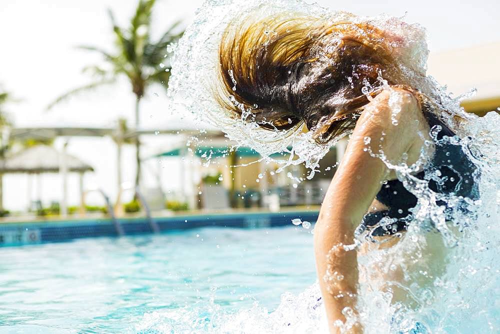 A teenage girl leaping out of the pool, Grand Cayman, Cayman Islands