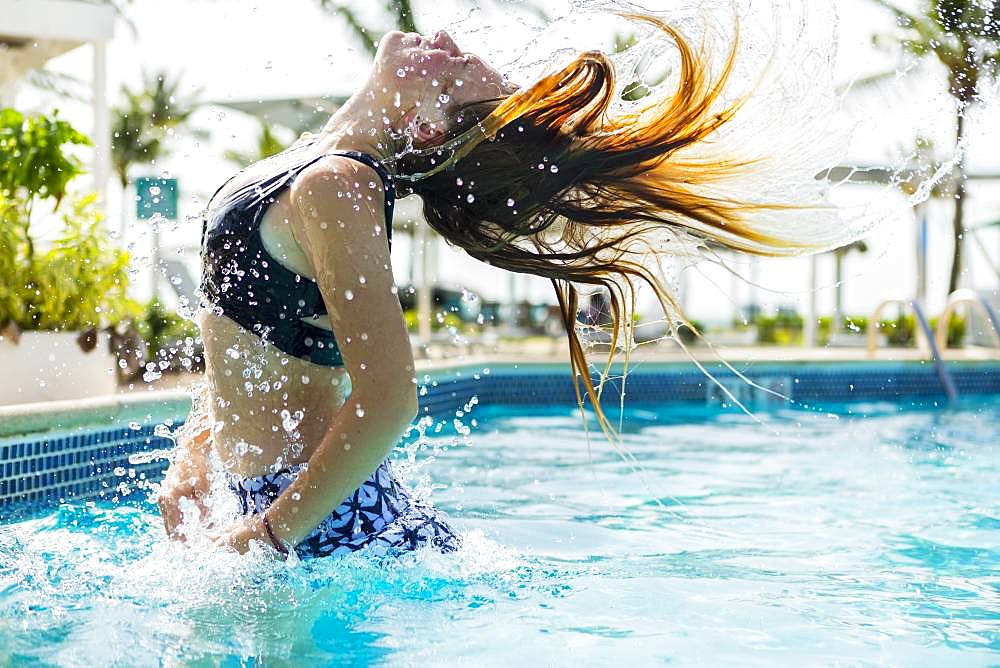 A teenage girl leaping out of the pool, Grand Cayman, Cayman Islands